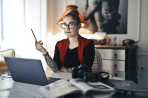 Tattooed woman sits at a laptop to increase productivity.